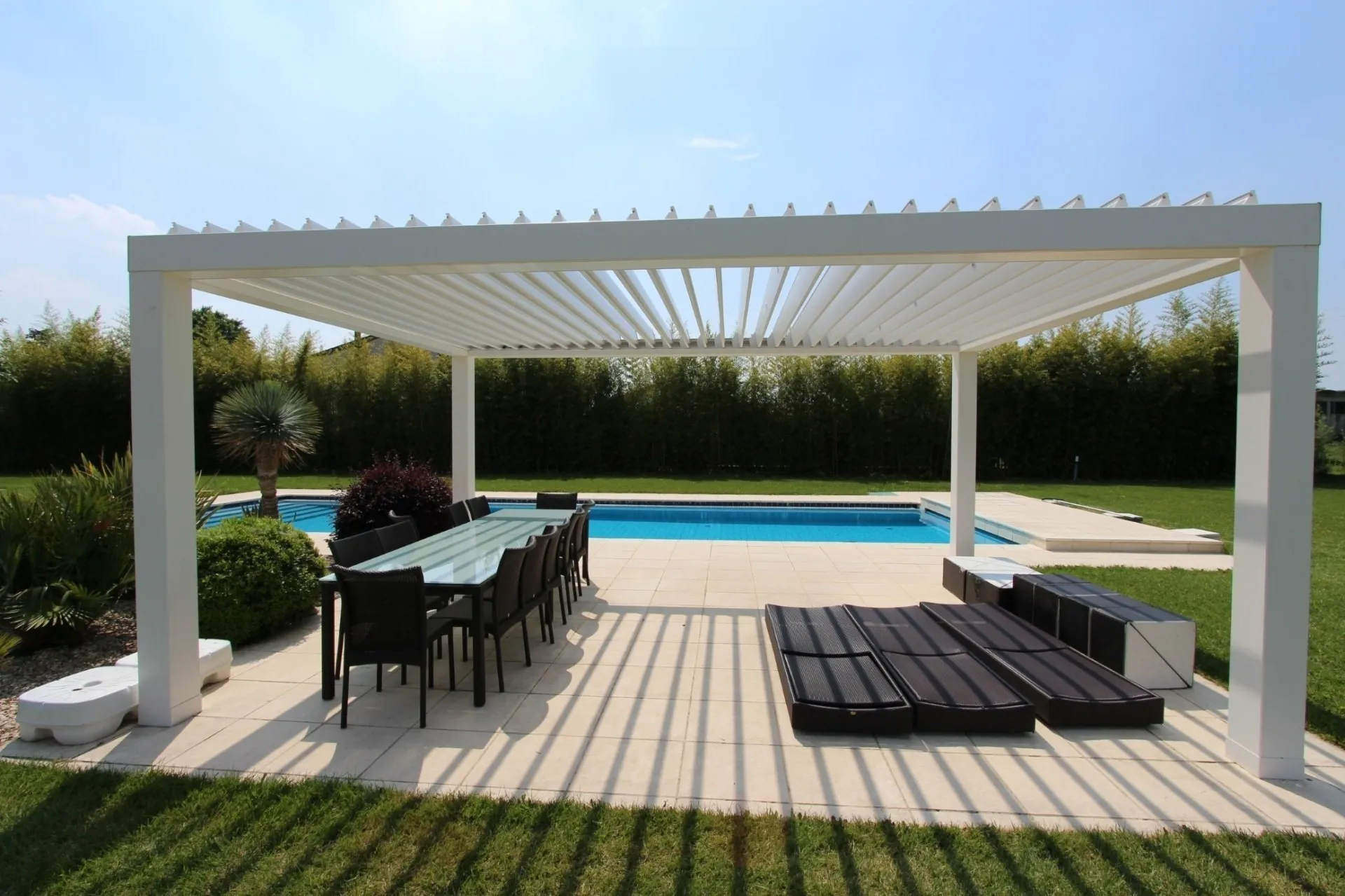 Pergola bioclimatica bianca a bordo piscina con tavolo da pranzo